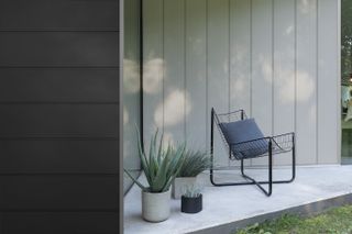 A grey clad exterior wall with a chair in front of it