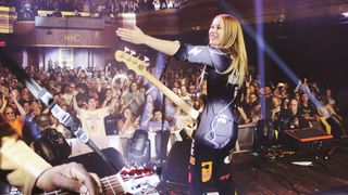 a rock band on stage in a crowded night club full of multicolored lights