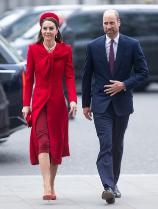 Kate Middleton, wearing a red dress and coat, and Prince William walking into the 2025 Commonwealth Day ceremony