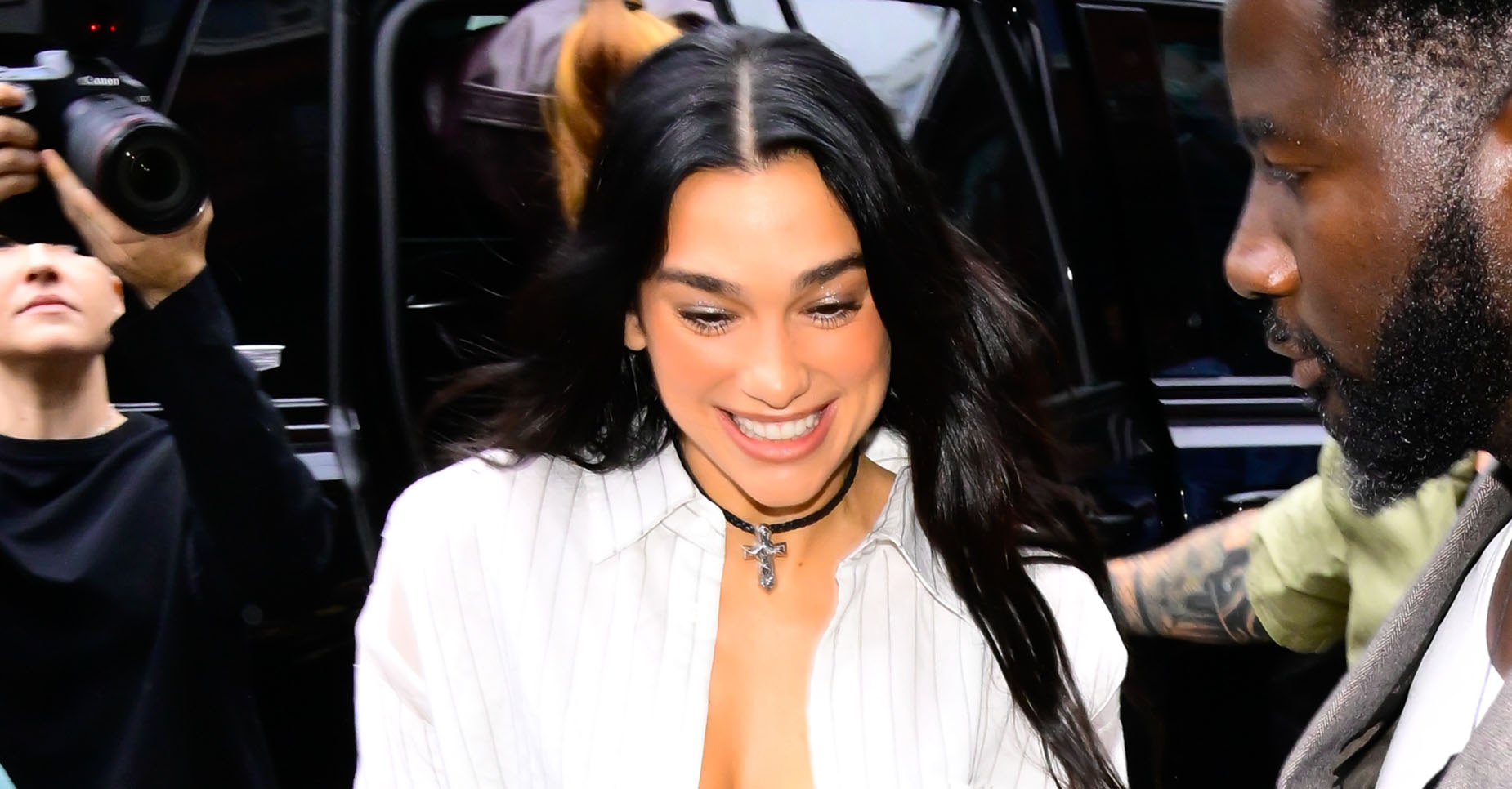 Dua Lipa wearing a striped button-down, gray maxi skirt, and black mesh heels