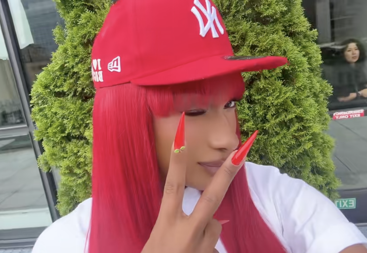 Megan Thee Stallion wearing a red hat with red hair and long red nails