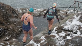 Two women preparing to go wild swimming on a snowy day