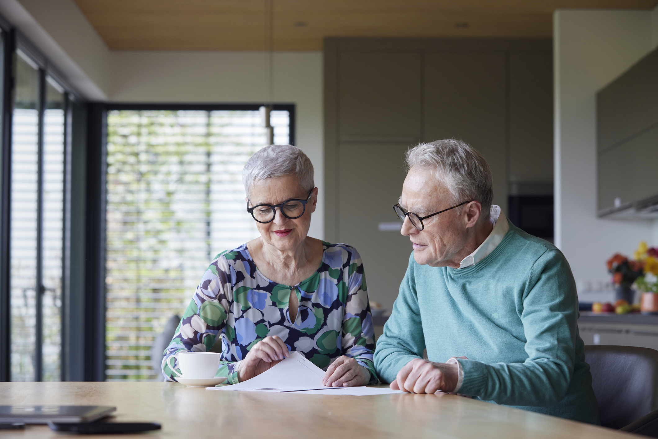 Senior couple sitting at table at home examining document