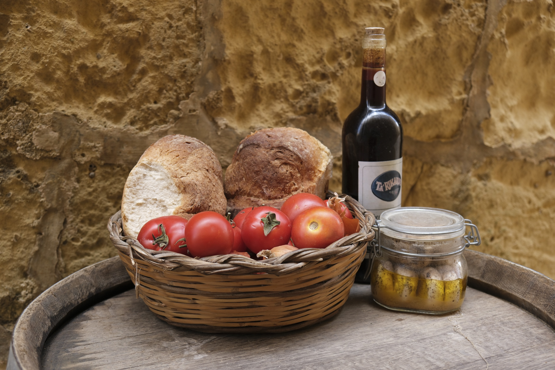Closeup of wine bottle, bread and tomatoes in basket