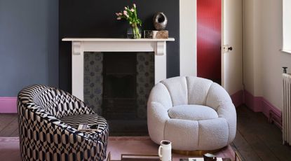 a room painted in white and black with a fireplace and comfy chairs