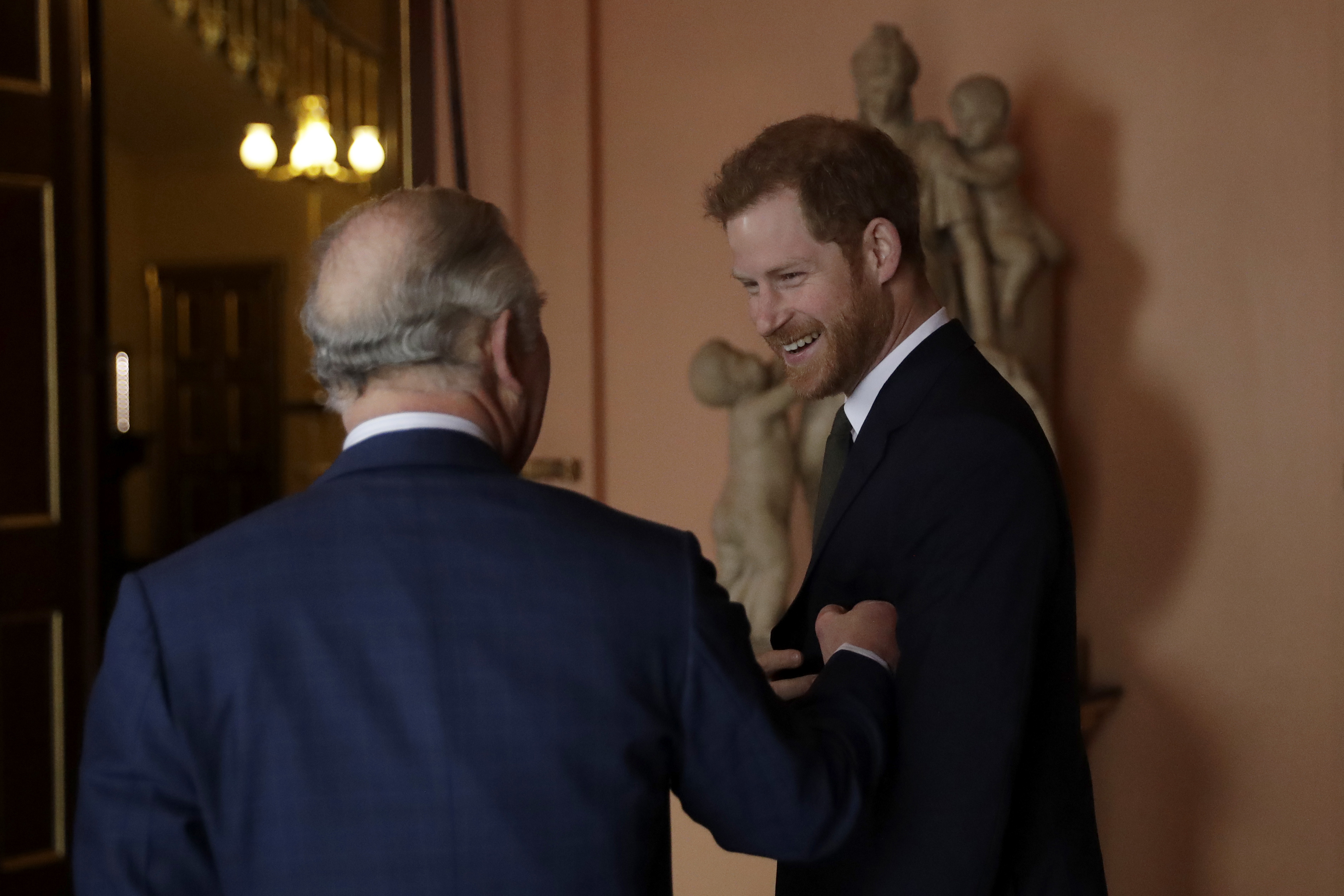 Prince Harry and King Charles laughing and touching arms