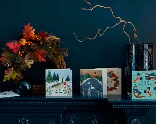 A fall/Christmas mantelpiece with christmas cards and a wreath