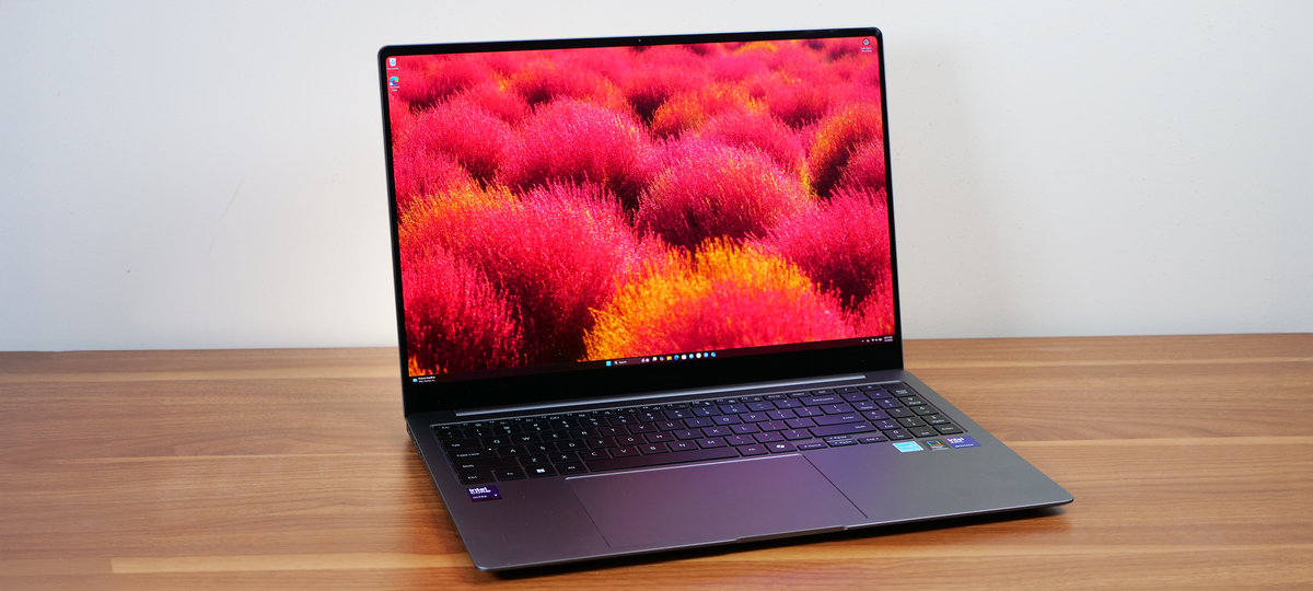 Samsung Galaxy Book 5 Pro slightly angled on a wooden table showing the desktop background on the display