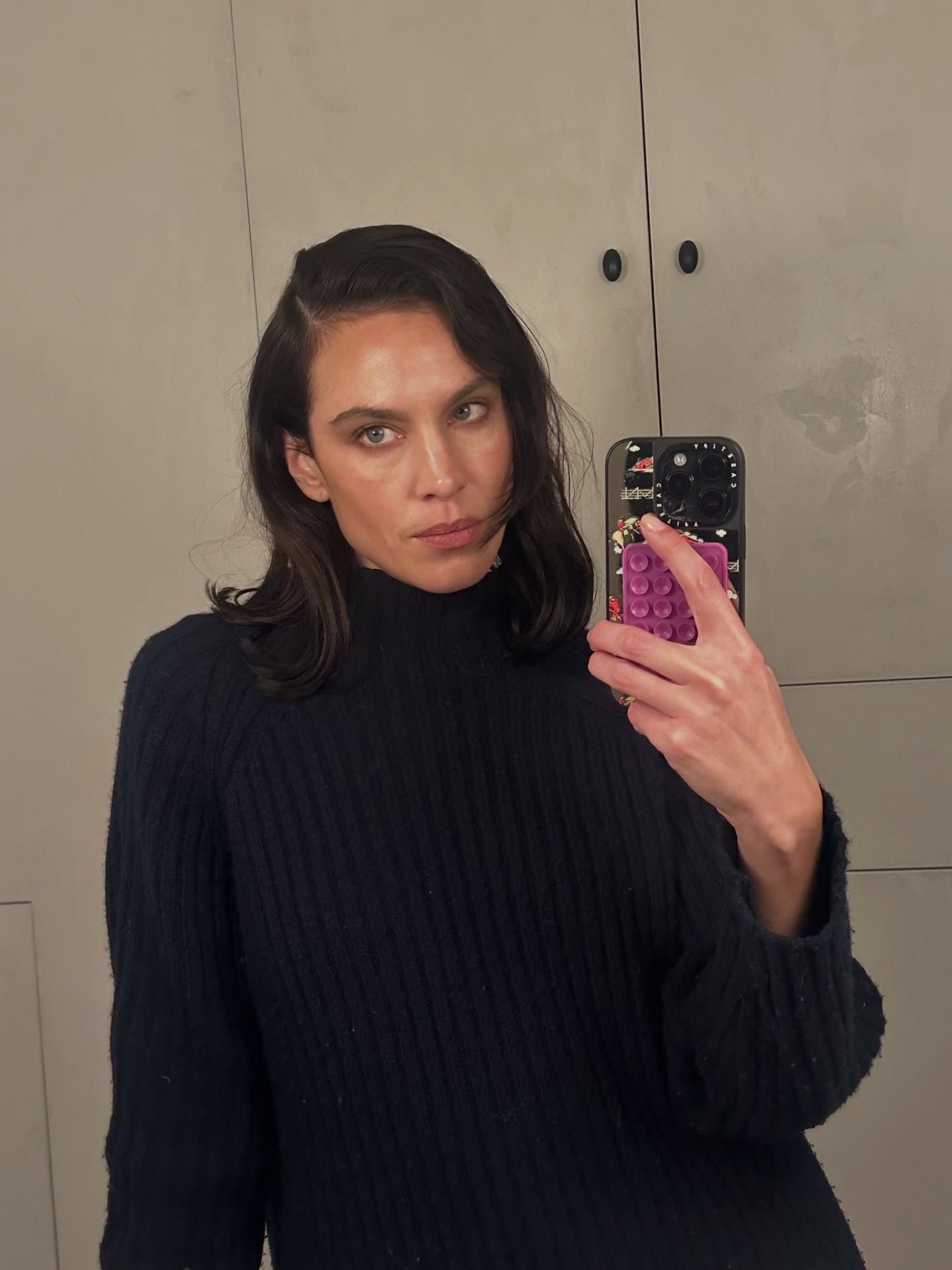 Alexa Chung wears a navy high-neck knit.