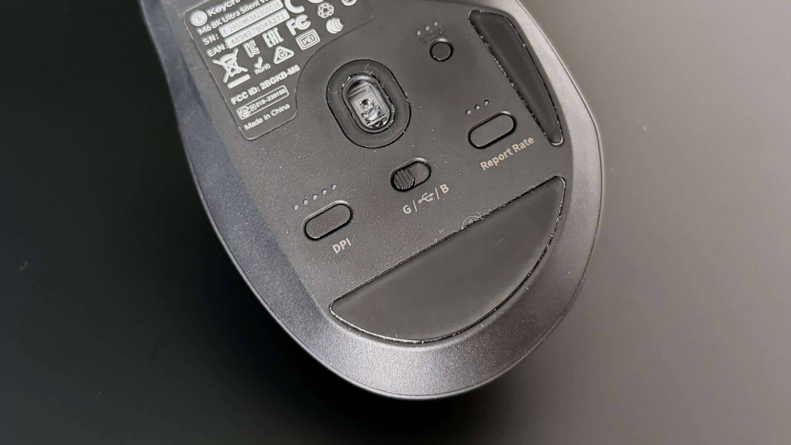 The base of the The Keychron M6 8K from above, showing off its sensor, DPI switch, mode switch, report rate switch and a Quick swap switch for Bluetooth devices .
