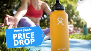 Woman meditating on exercise mat with Hydro Flask water bottle in front of her and TG price drop badge bottom left