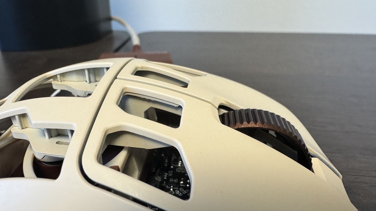 The Pulsar Feinmann F01 Noctua Edition gaming mouse on a wooden desk from the top left, close up