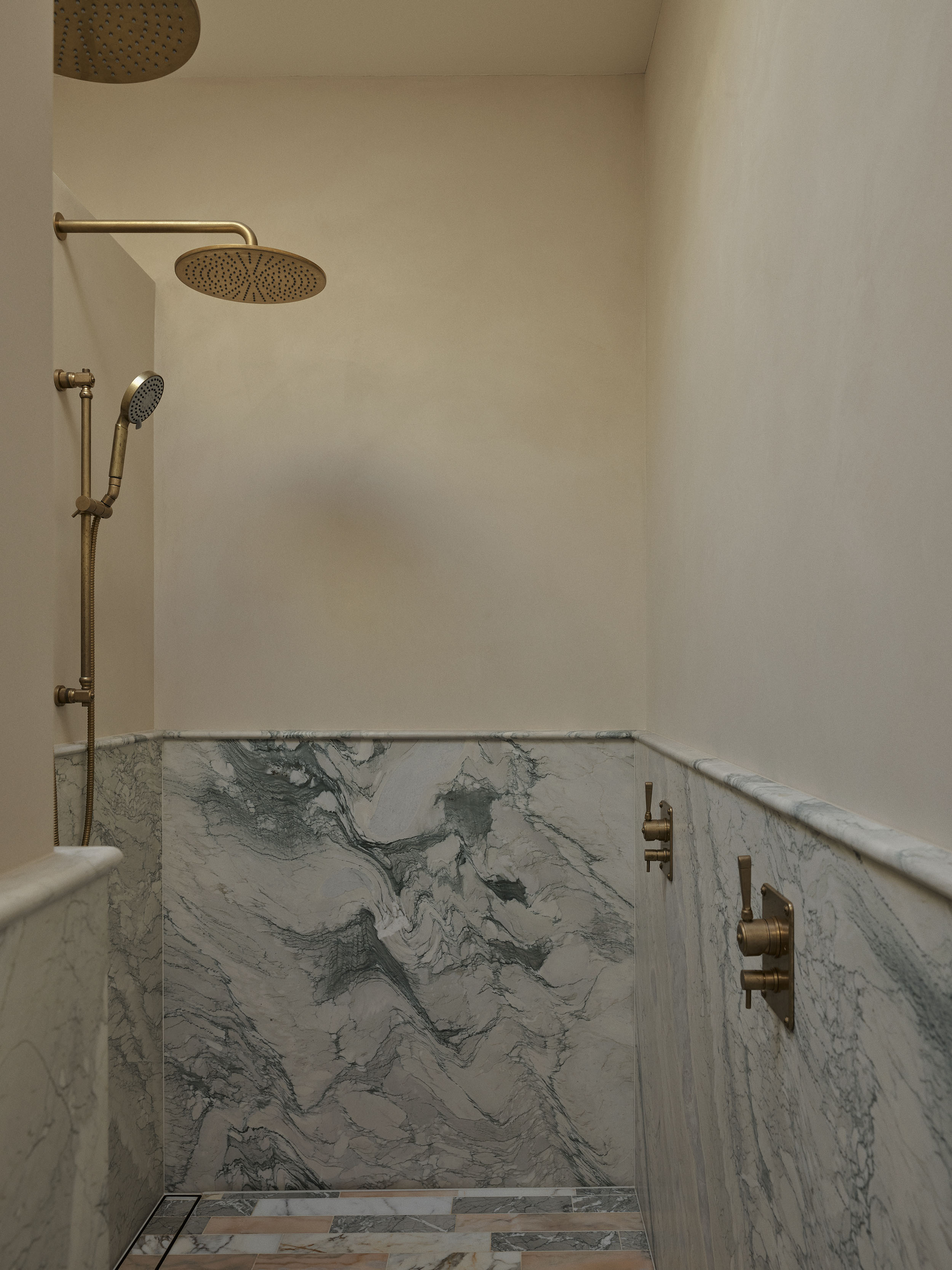 Walk-in marble shower with brushed brass fixtures in the primary bathroom of Smac Studio's renovated Art Deco residence in Woollahra, Sydney.