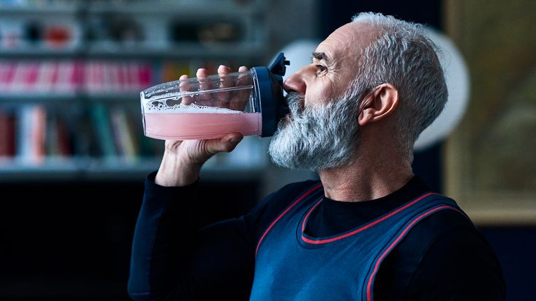 Elderly man drinks a freshly blended smoothie from bottle