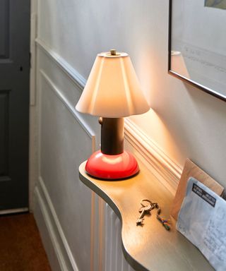 A table lamp on a wooden shelf in a small entryway