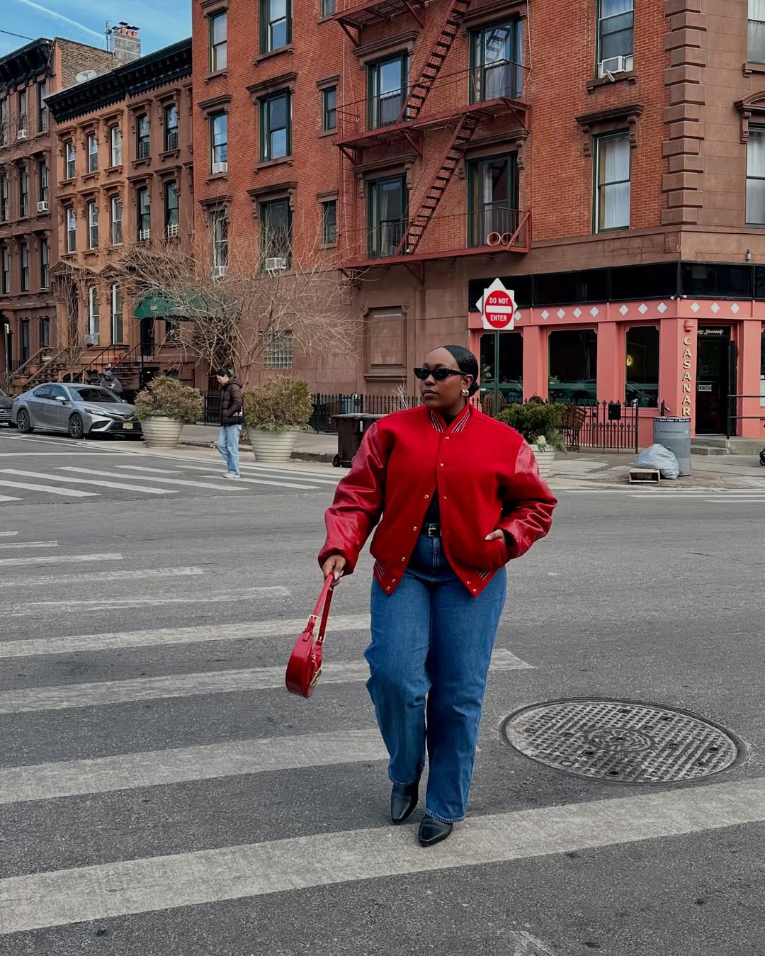 @aniyahmorinia wears slim-straight jeans with a red varsity jacket