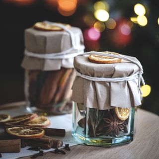 Pot pourri in glass jars including dried orange slices, cinnamon sticks and spices