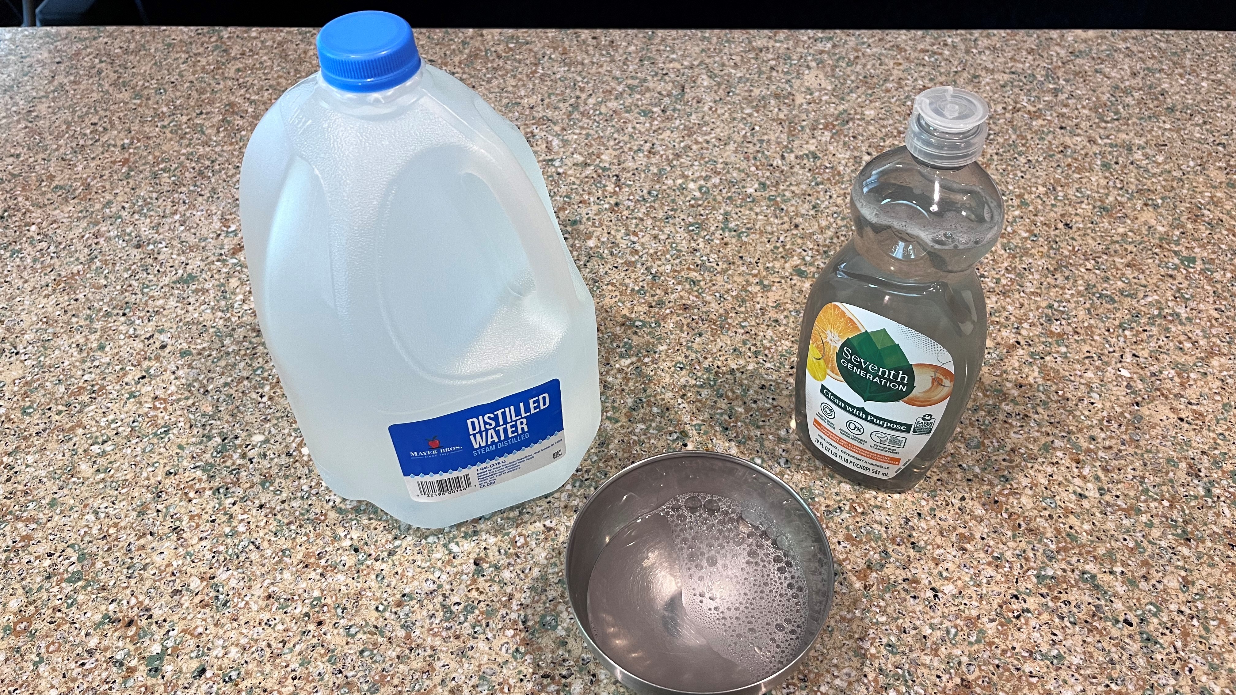 distilled water and dish soap with metal bowl on countertop