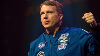 a man in blue jumpsuit does a fist pump