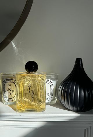 Diptyque Boise corse perfume bottle on mantle with candles