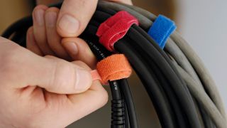 A man holds guitar cables with velcro ties on them