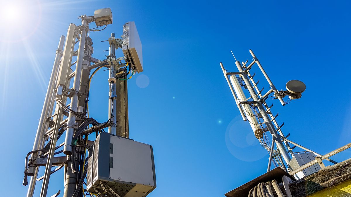 5G masts and network equipment, shot from below against a blue sky