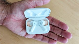 Listing image for best fake AirPods showing the Donner DoBuds One wireless earbuds in reviewer's hand.