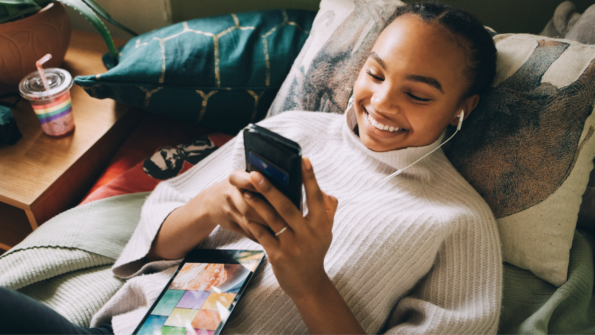 Black woman looking at her phone in bed