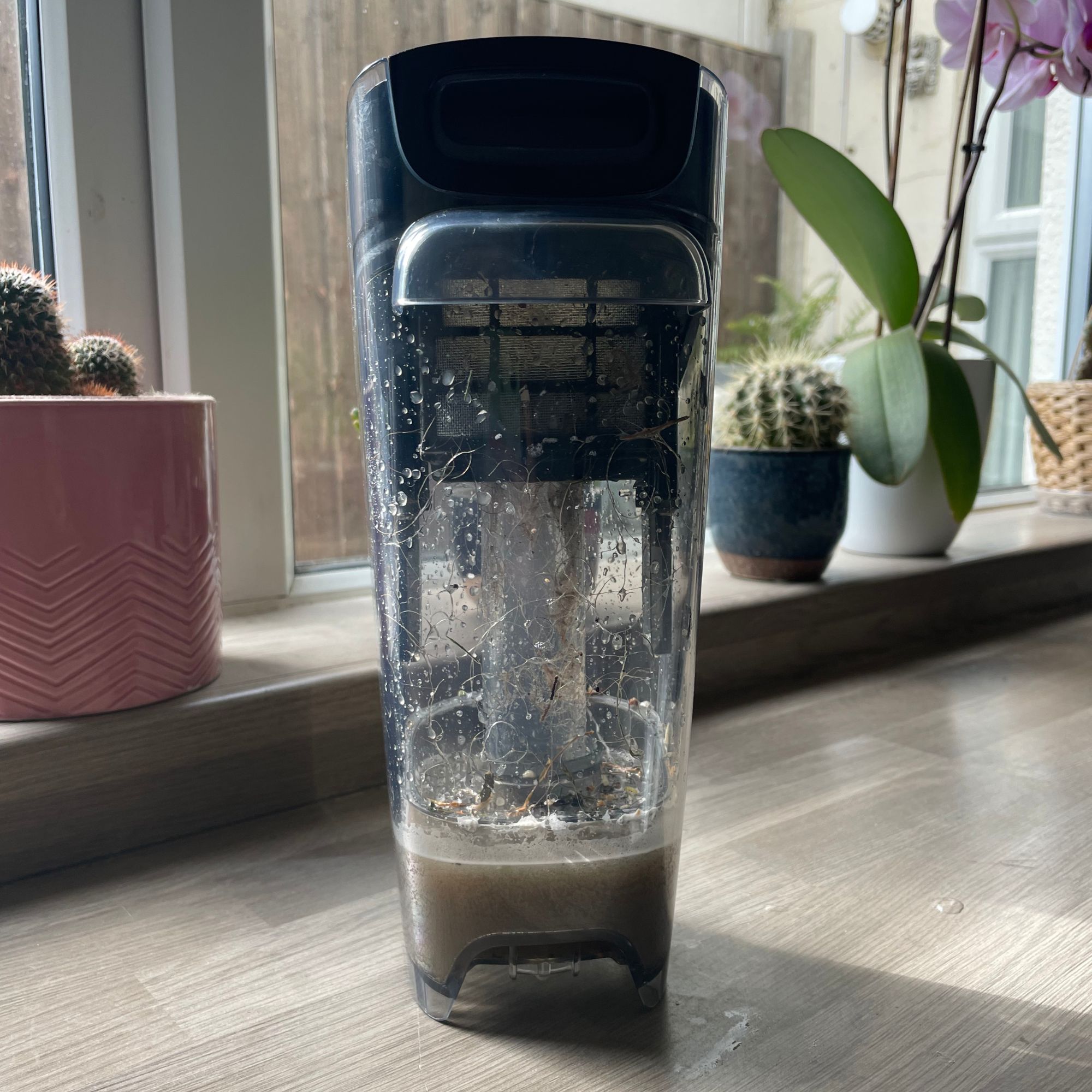 Dirty water tank of the Bissell Crosswave Omniforce Edge sitting on kitchen worktop
