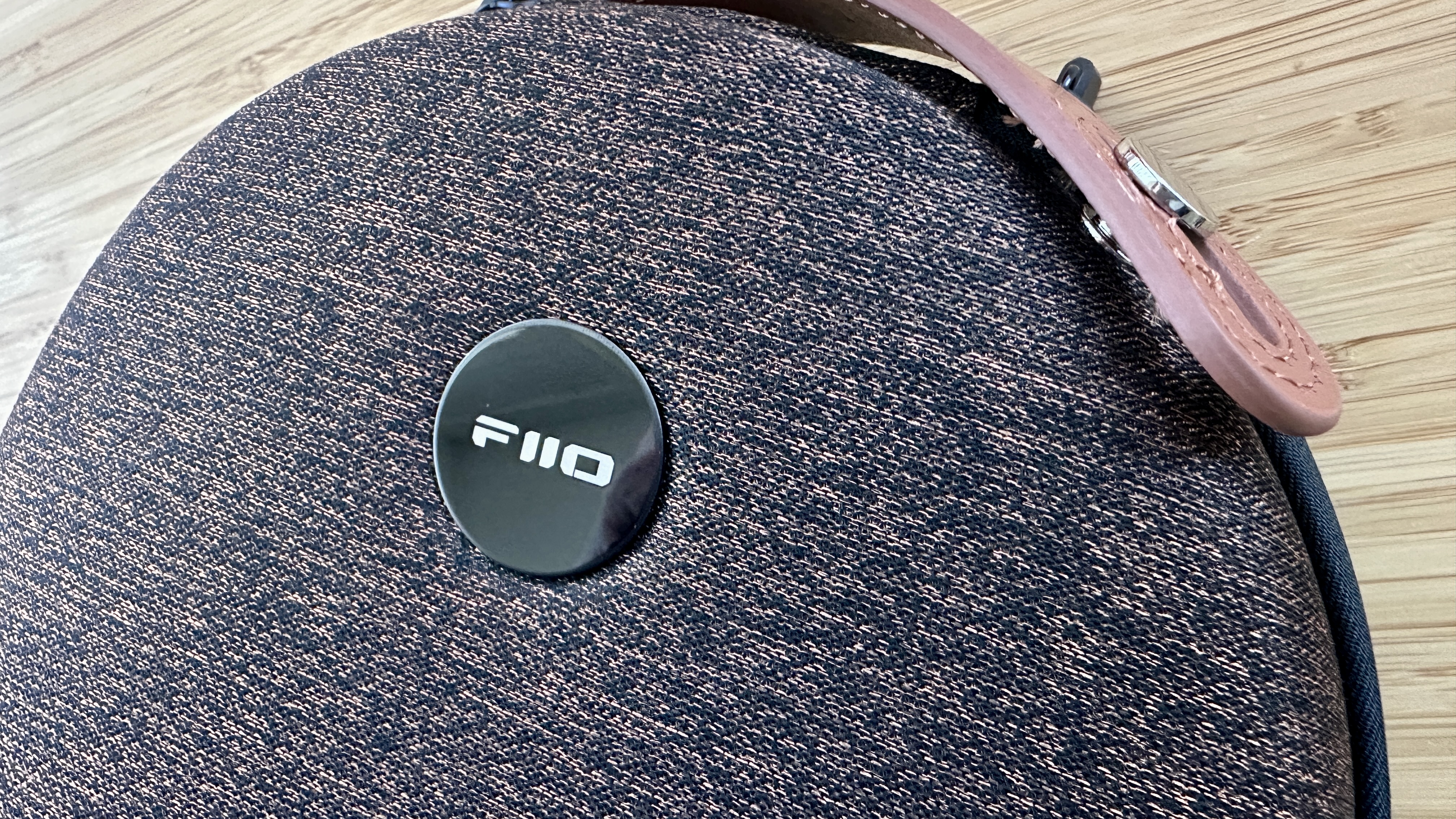 Hard carry case of the FiiO FT13 closed-back over-ear headphones on a wooden surface.