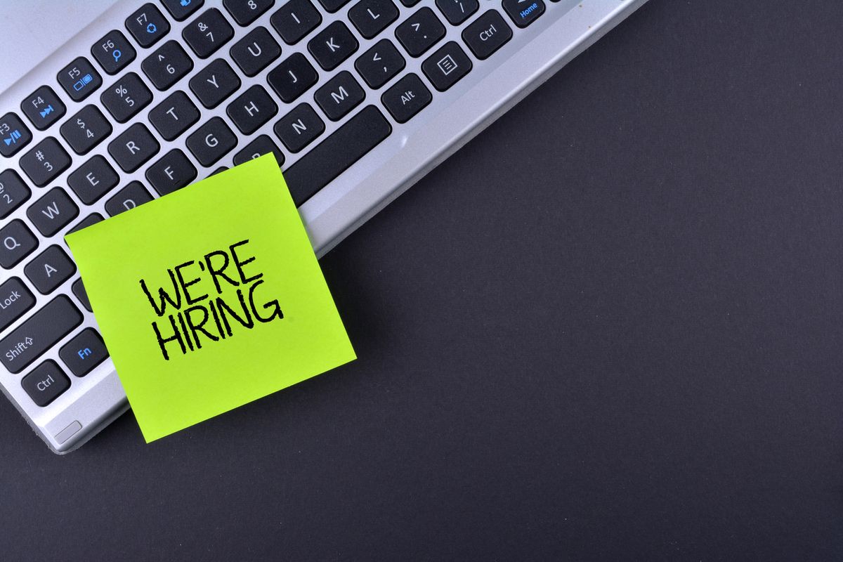 A post-it note stuck to a laptop keyboard reading &amp;quot;We&amp;#039;re hiring&amp;quot;