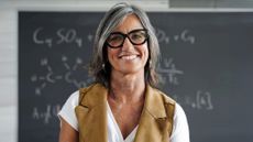 Portrait of senior female teacher standing in front of a chalkboard