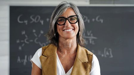 Portrait of senior female teacher standing in front of a chalkboard