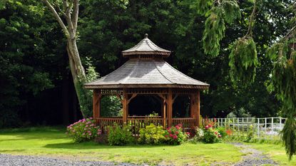 A gazebo in a back yard next to a wooden fence Getty Images 134178251