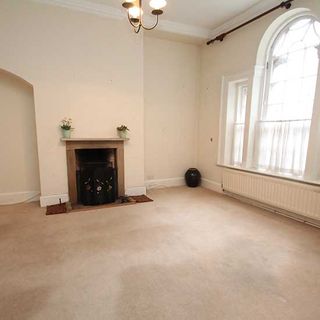 bedroom with white walls polished flooring and arched windows