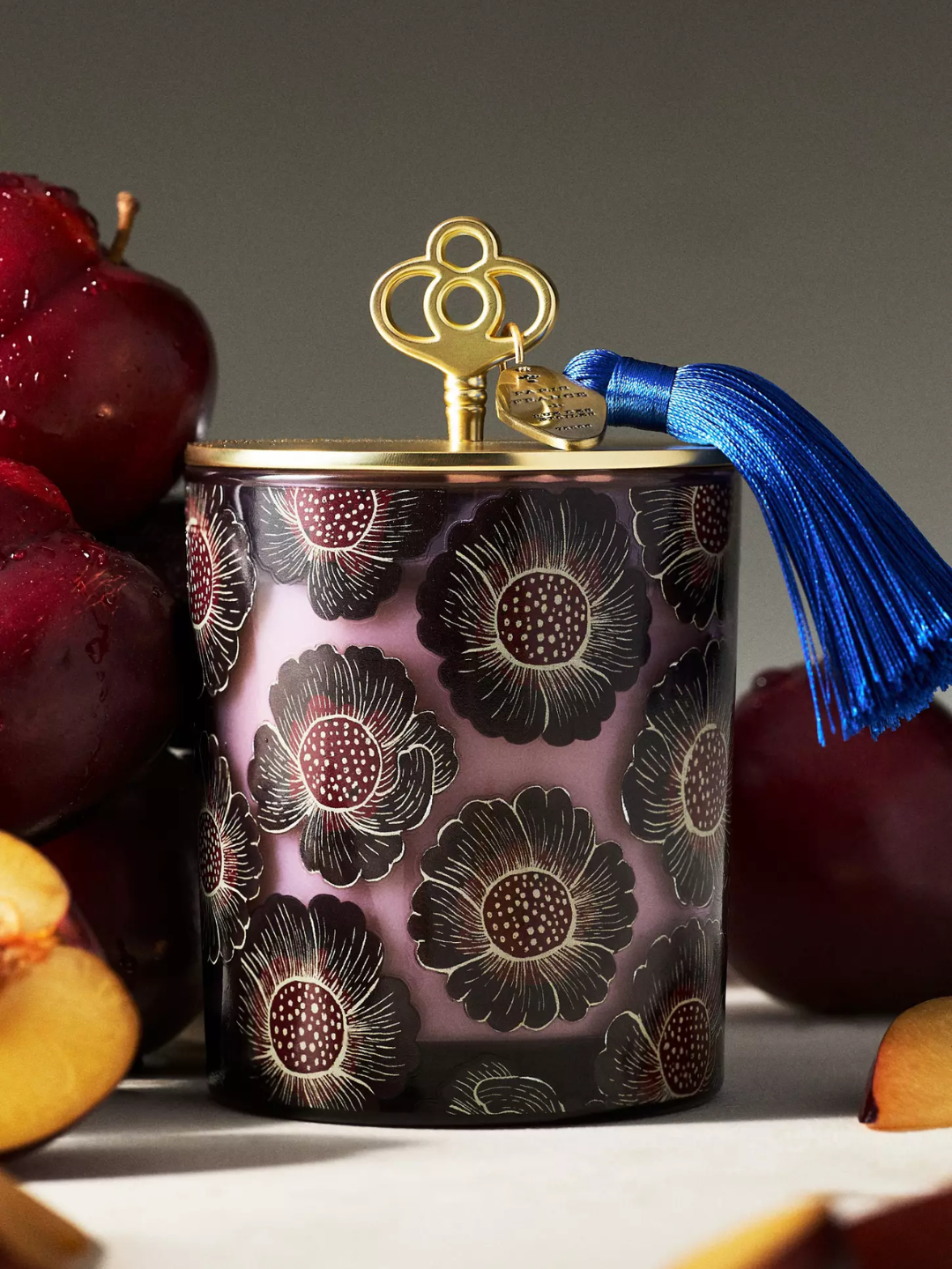 A floral patterned candle with a vanilla and plum scent with a gold tasseled lid from Anthropologie