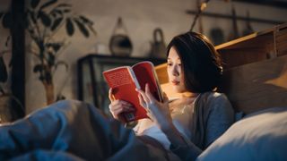 A woman reads a book in bed before going to sleep