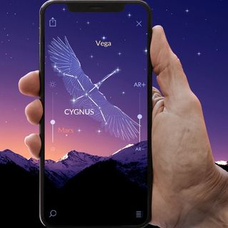 Star Walk 2 displayed on a smartphone in a person's hand showing the Cygnus constellation.
