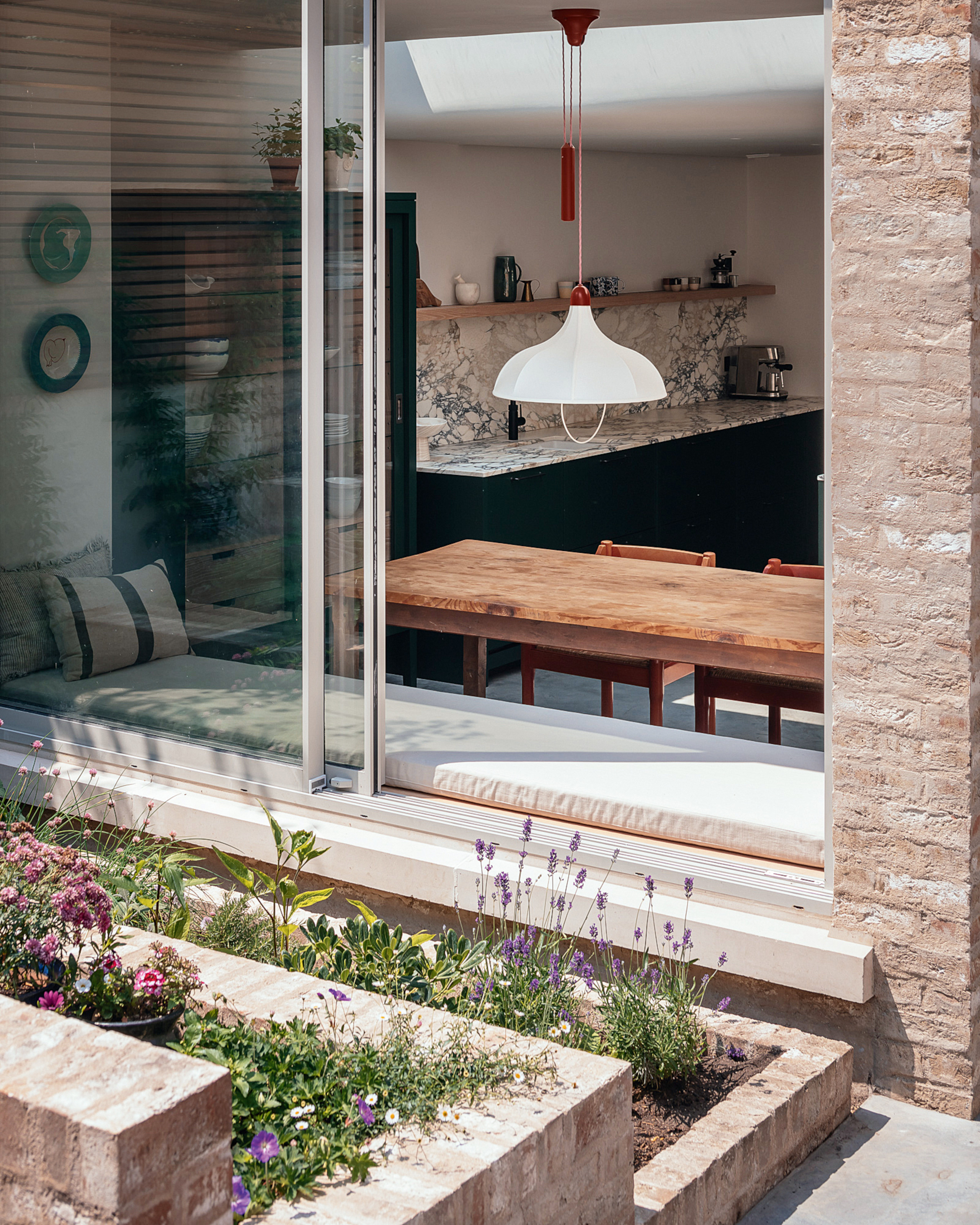 Close-up of tiered brick planters leading to a sliding window with indoor window seat