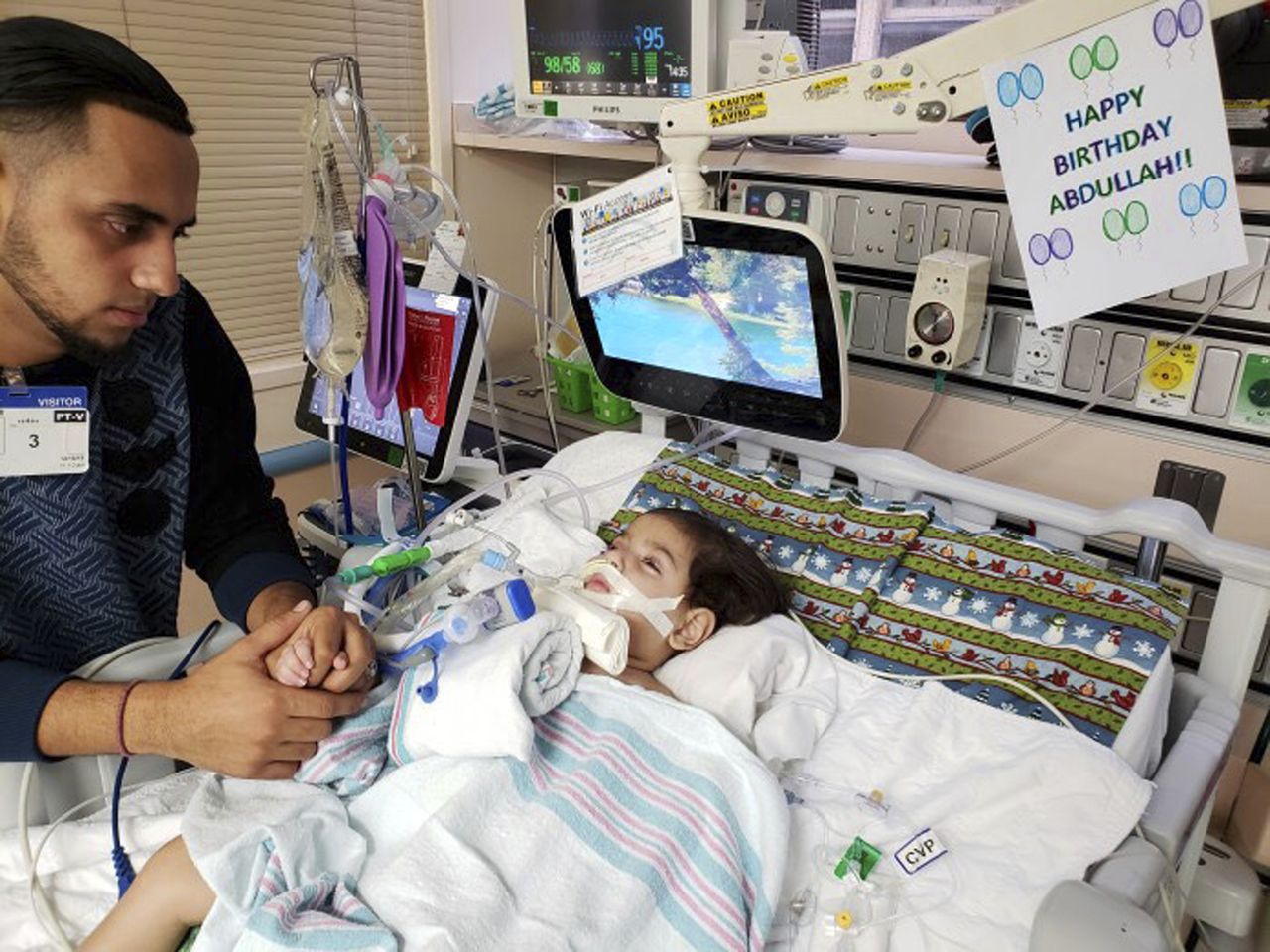 Ali Hassan with his dying 2-year-old son Abdullah.