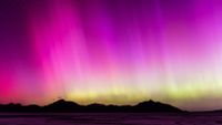 ribbons of light appear across the sky as the northern lights are vivid yellow pink and purple.