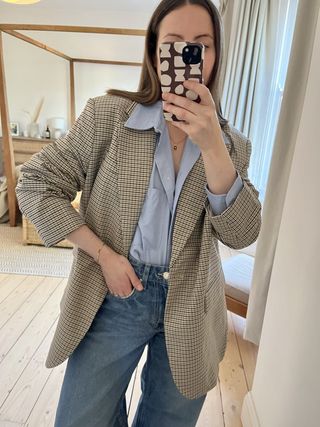 Woman in mirror wears check blazer and blue shirt