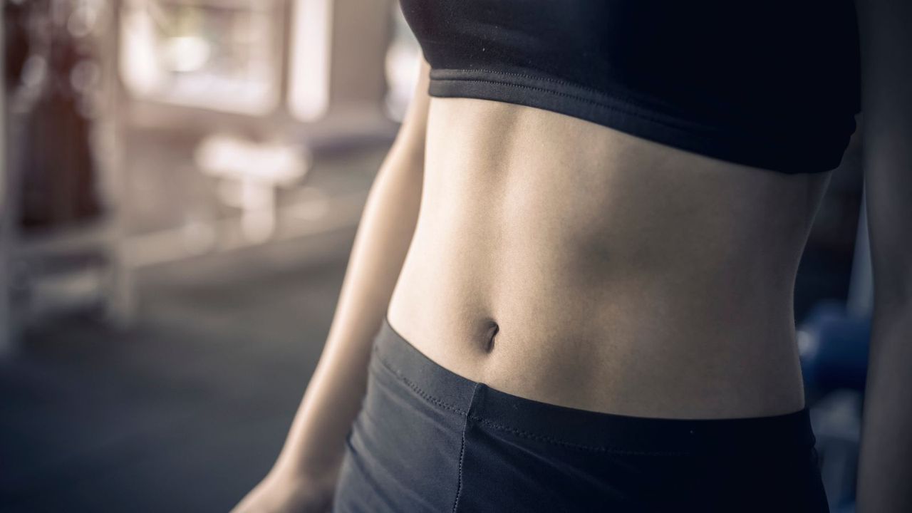 The midsection of a woman standing in a gym 