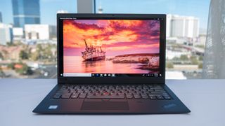 A Windows 10 business laptop on a white surface in front of an office window