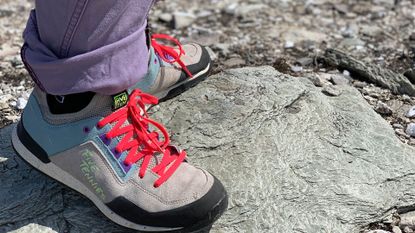 Woman wearing Adidas Five Ten Guide Tennies on rocky ground