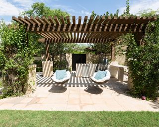 Patio with wooden pergola and climbing plants framing hammock chairs