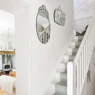 white wall with stairway and mirror on wall