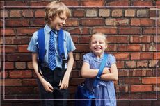 Siblings stood by a wall for their back to school photo