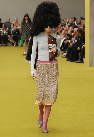 Woman on Gucci runway in feathered hat and Gucci skirt