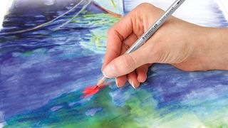 best watercolour pencils: close up of hand creating a watercolour picture with a pencil